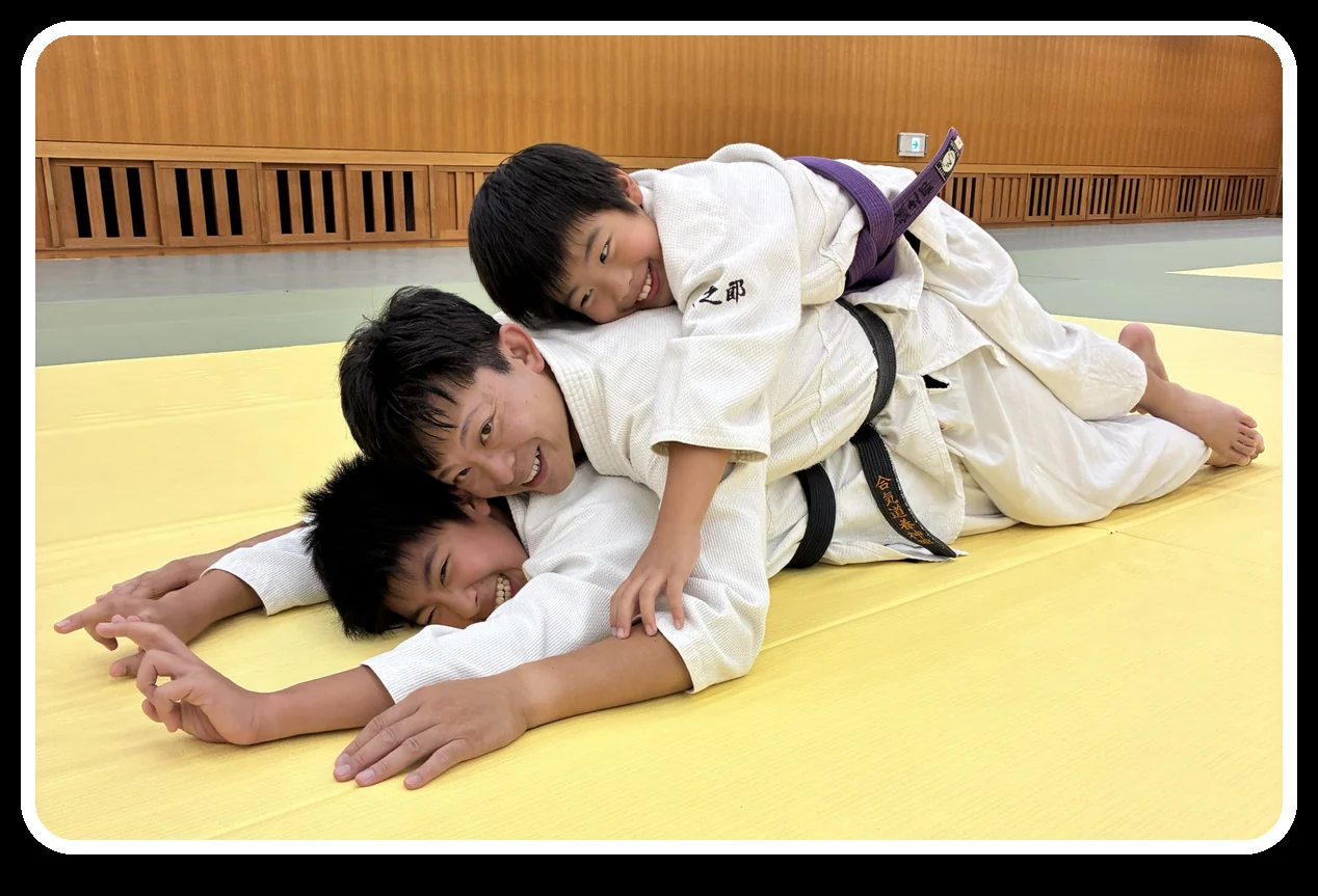 合気道の稽古で、子どもと指導者が笑顔で触れ合う様子